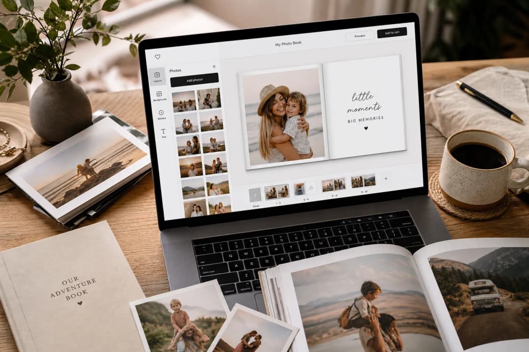 Personalized photo album being created online on a laptop with printed photos nearby